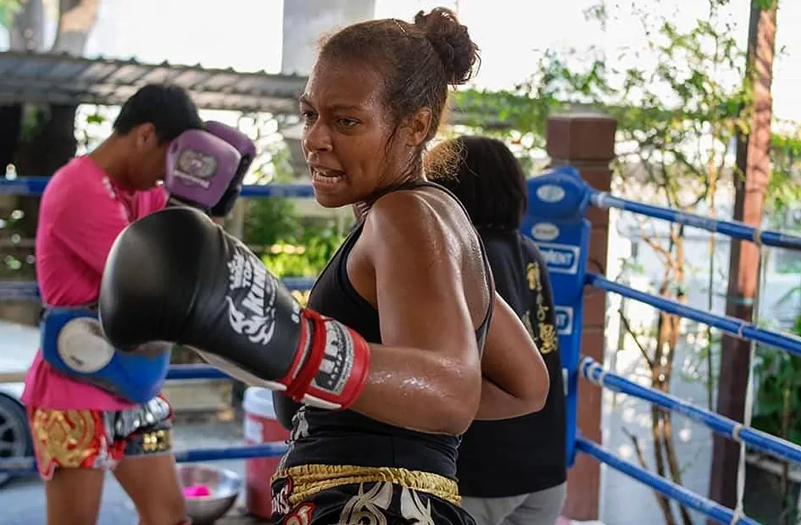 Female student in 1-Month Muay Thai Training Class for Fighters at Eminent Air Boxing Gym, showcasing intense and focused training atmosphere.