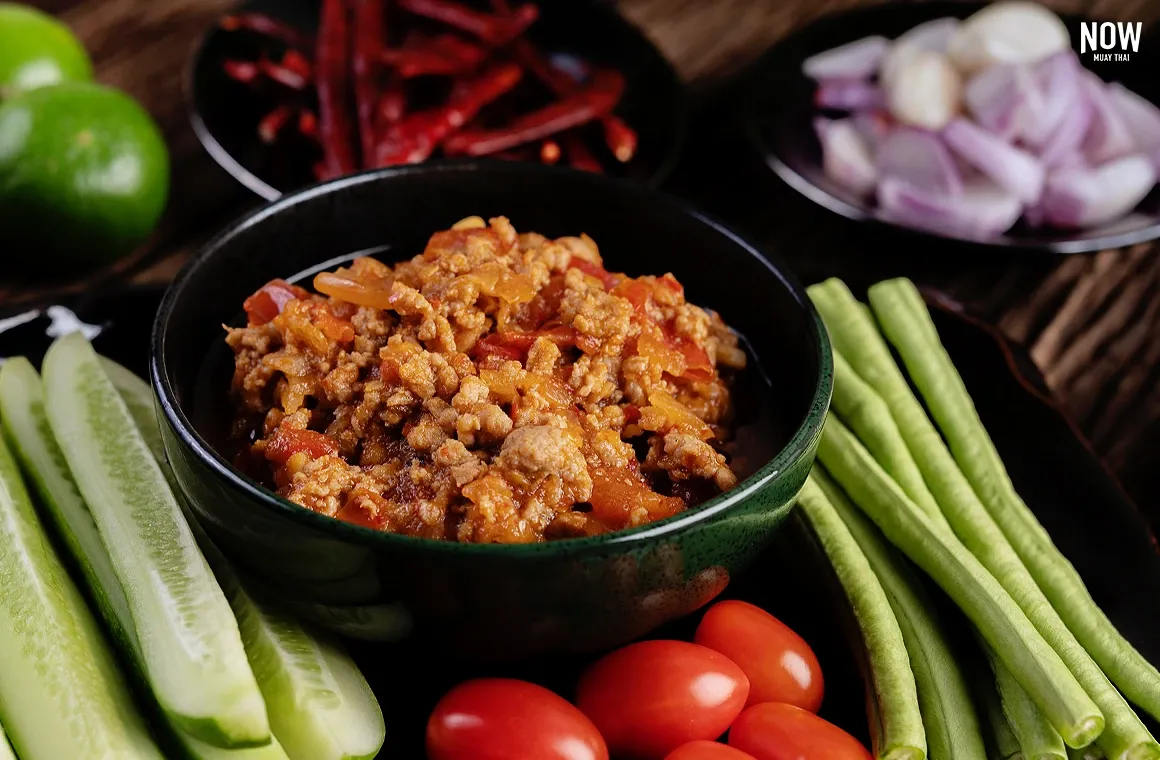 Nam Prik Ong, a signature northern Thai chili dip made with tomatoes and dried chilies, cooked into a rich orange paste. Its flavor is tangy, salty, mildly spicy, and slightly sweet, often enjoyed with fresh vegetables.
