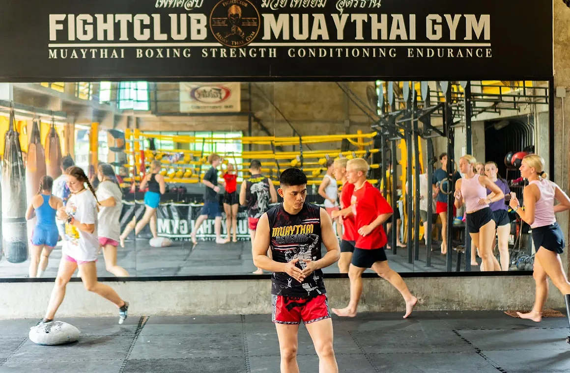 Kru Huak, the lead trainer of Fight Club Muay Thai Gym in Udon Thani, teaches a group of students during the warm-up phase of a Muay Thai class.