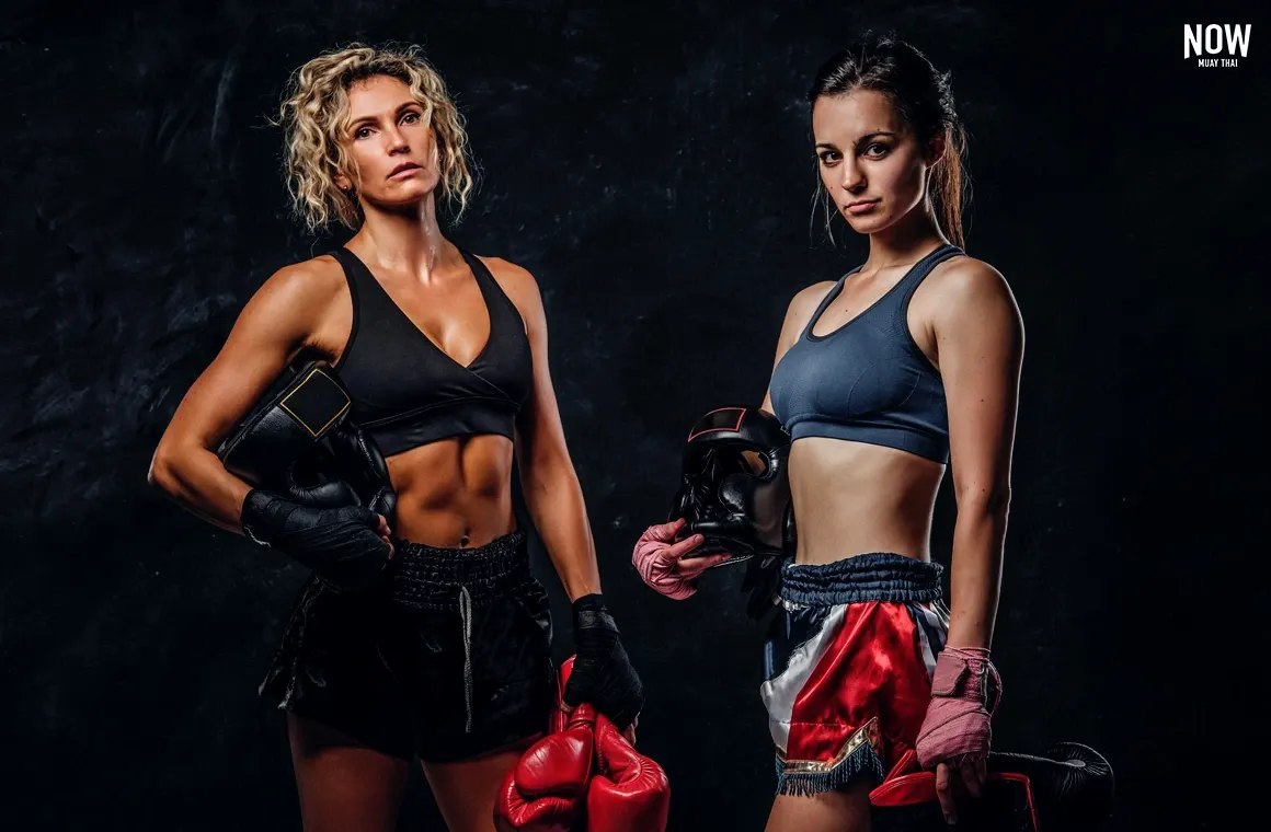 A shot of two professional female kickboxing fighters posing with gloves and protective gear, looking at the camera