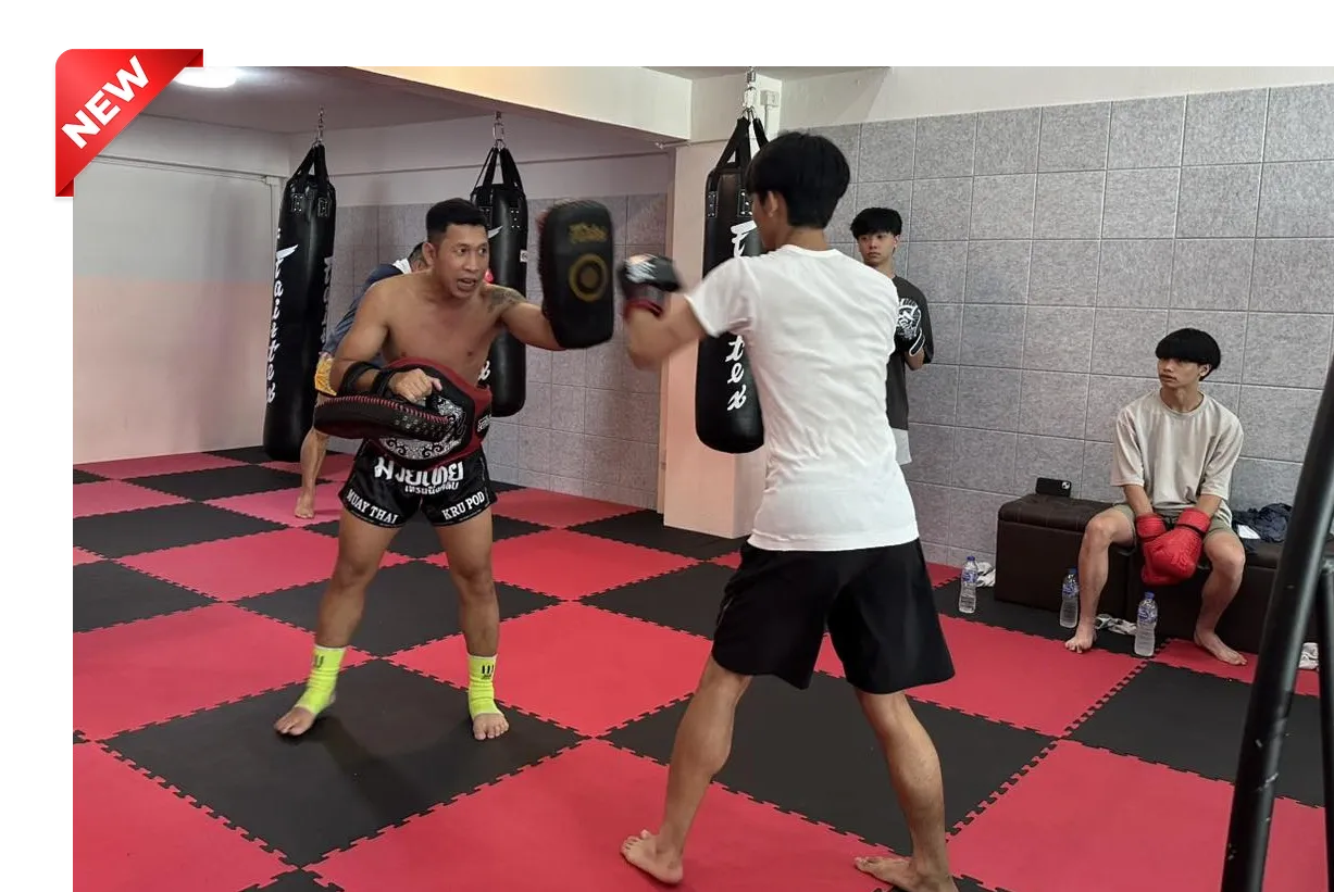 Trainer holding Thai pads while a student practices striking during a Muay Thai class at Kru Frame Muay Thai Training Club in Chiang Mai