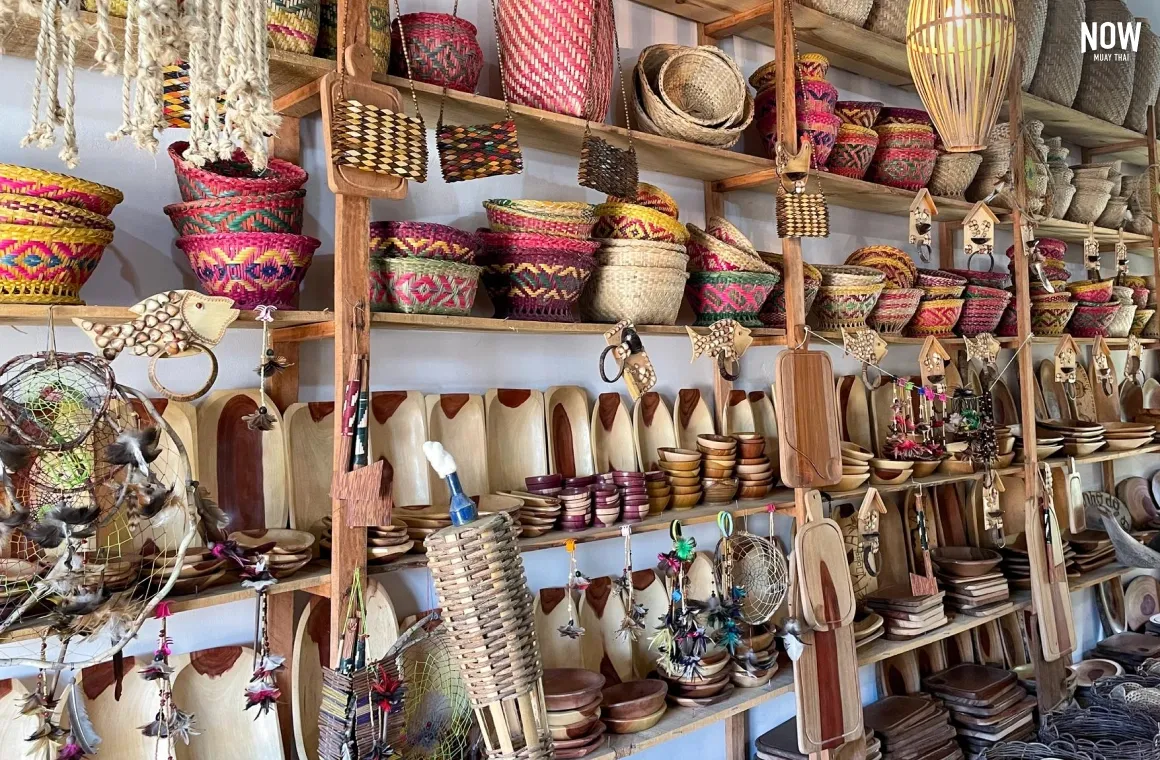 A close-up display inside a shop at Pai Walking Street, Mae Hong Son, Thailand, showing various handmade items like cups, bags, and souvenirs neatly arranged on racks and shelves.