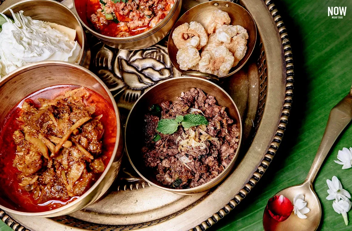 Traditional Khantoke dining in Chiang Mai featuring northern Thai dishes — gaeng hang lay curry, larb moo kua, nam prik ong, and crispy pork cracklings.