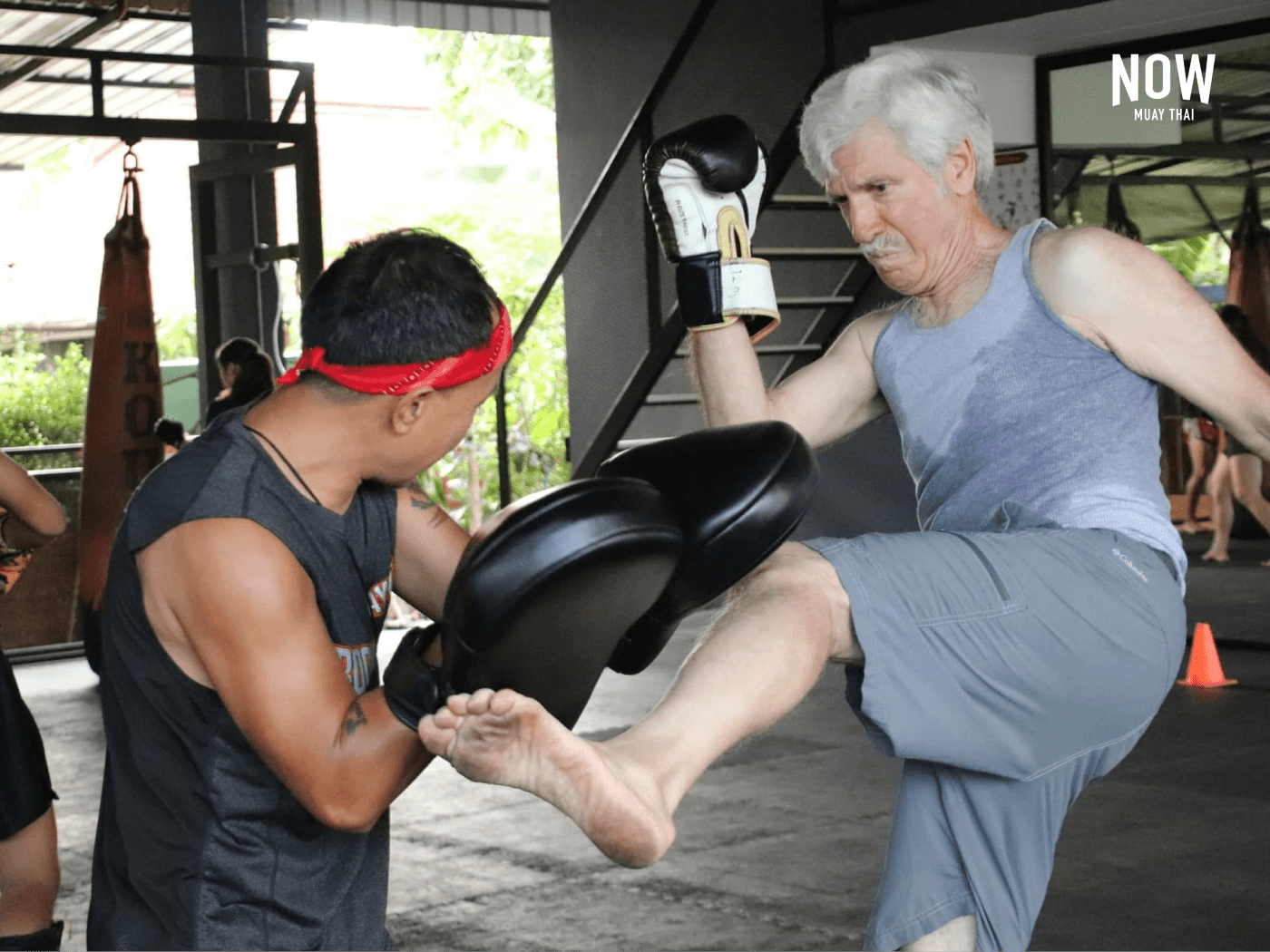 An elderly gentleman practicing pad work at Boon Lanna Muay Thai gym in Chiang Mai