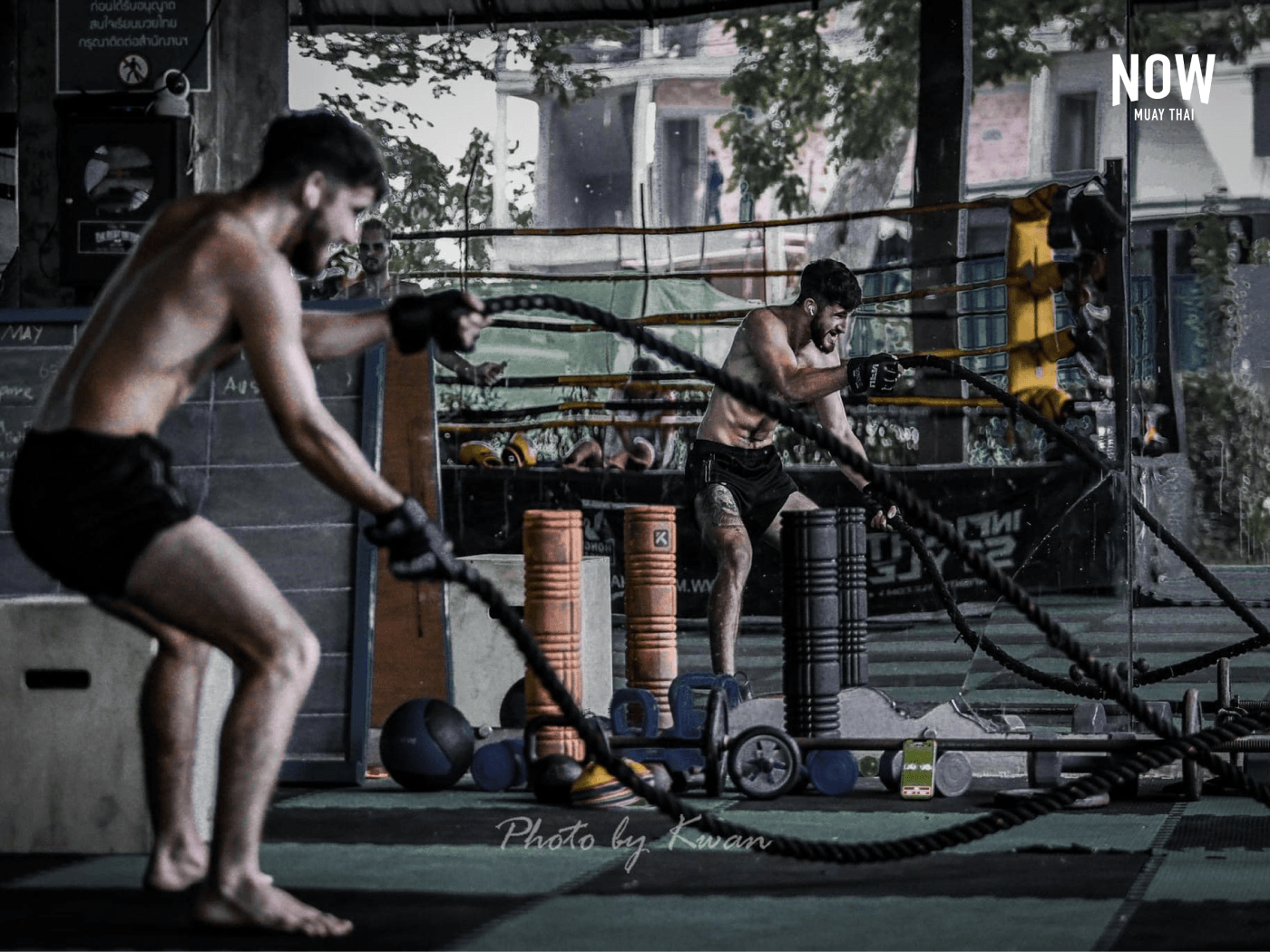 Man training with battle ropes in front of a mirror wall at the Hongthong Muay Thai Gym in Chiang Mai.