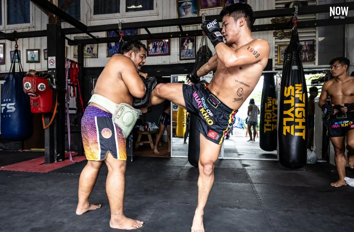 a man practicing muay thai kicks with a professional trainer at FA Group Bangkok