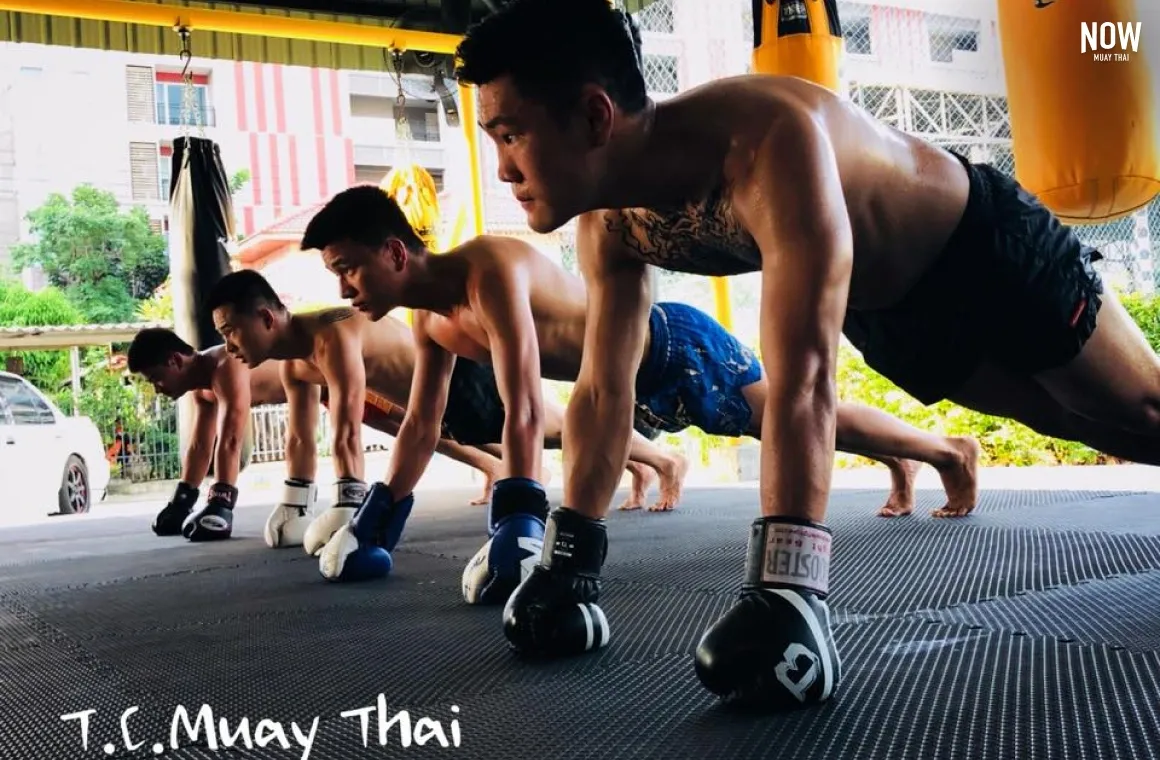 4 man doing plank with their boxing gloves at TC Muay Thai Gym in Bangkok