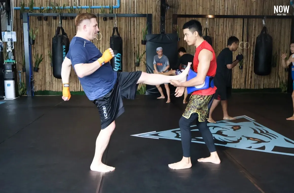 a trainer explaining muay thai kicking techniques to a man at Tiger Eye Muay Thai and MMA Gym in Bangkok