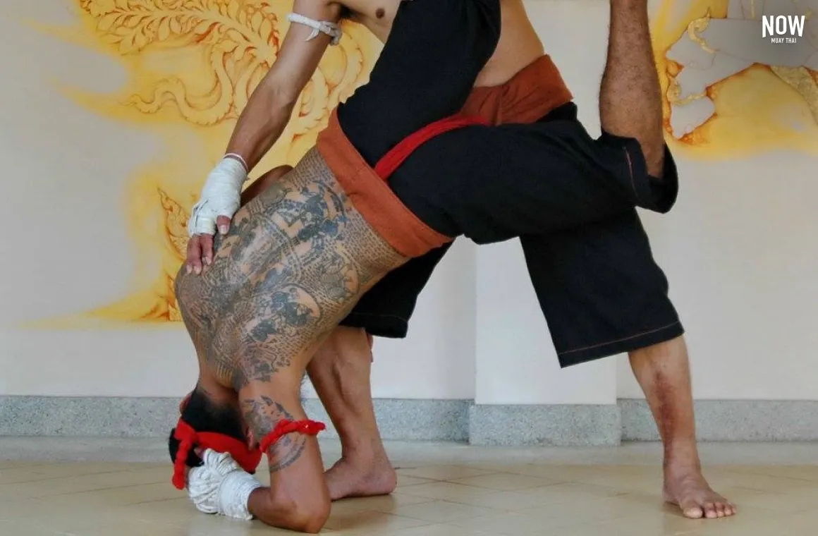 2 men fighting, one is upside down, standing on his elbow and his head, while the other one holds his right leg in the air at ThaiAchira Bangkok