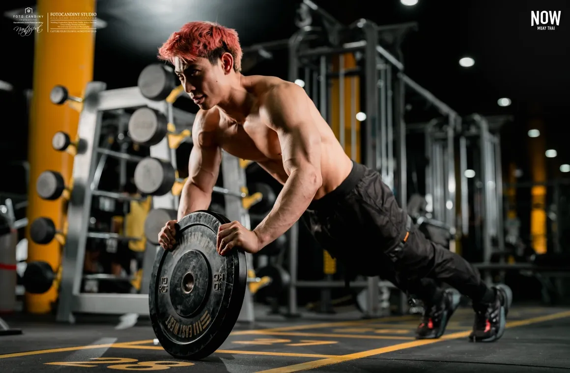 a men balancing a plank on a dumbbell at Marrok Muay Thai and Fitness Gym Bangkok