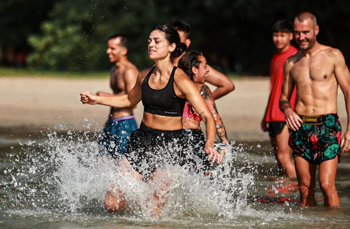 A group of Muay Thai enthusiasts training on a sunlit beach in Thailand, surrounded by a joyful and energetic atmosphere. The image captures why people from around the world are drawn to experience the unique Muay Thai journey in Thailand, combining intense training, beautiful landscapes, and a vibrant cultural experience.