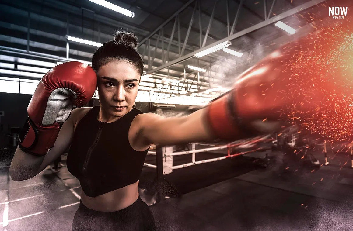 A woman practicing Muay Thai demonstrates her powerful punch, showcasing strength and confidence gained from daily training. Consistent practice builds physical power and reveals her full potential in the art.