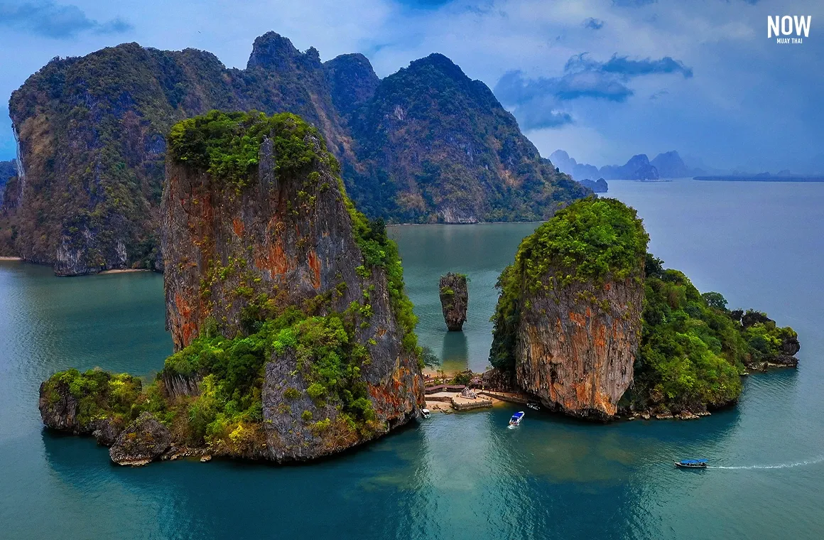 A breathtaking bird's-eye view of James Bond Island in Phang Nga Bay, showcasing the iconic limestone karst surrounded by emerald green waters and lush cliffs.
