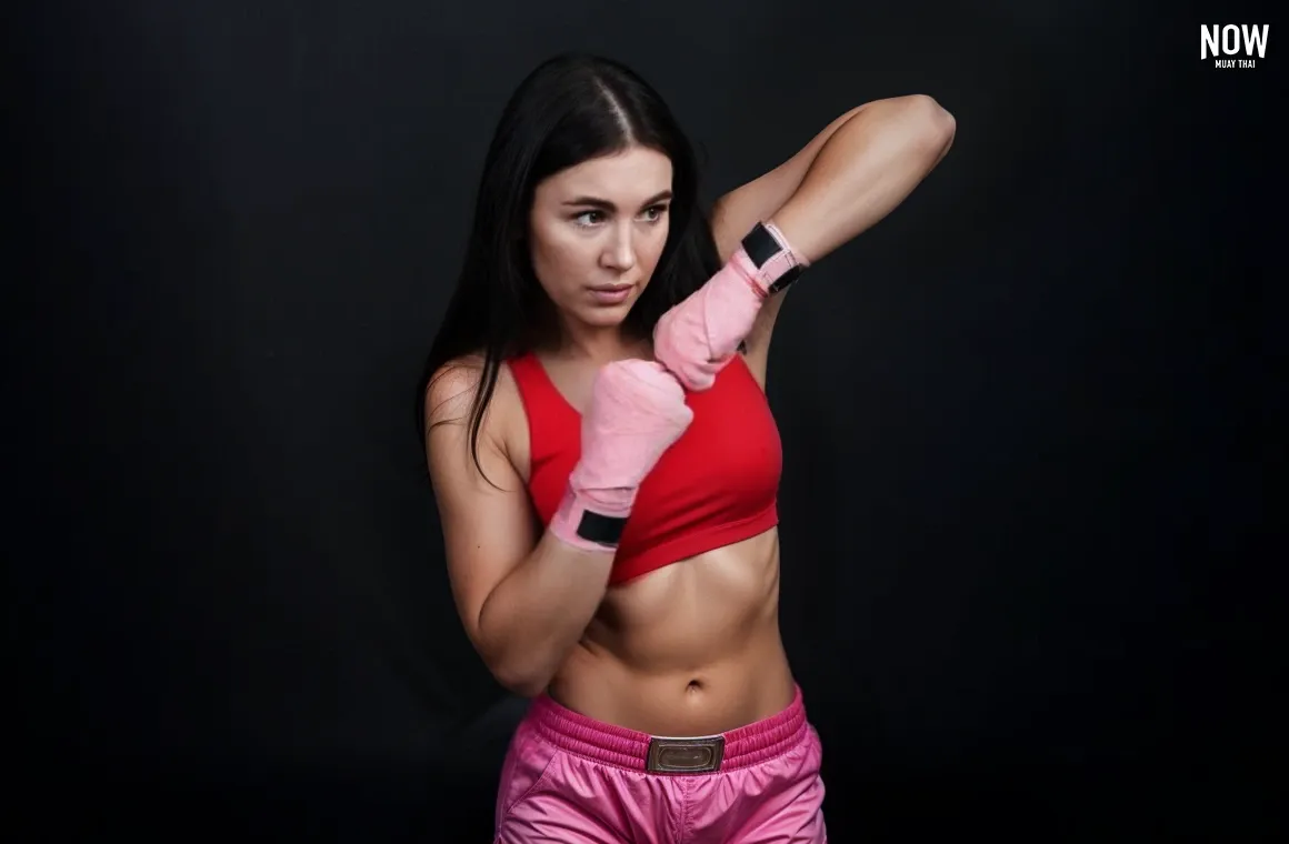 A woman practicing shadow boxing with high-speed punches, elbows, kicks, and knees, integrating footwork drills during a Muay Thai training session for effective calorie-burning.