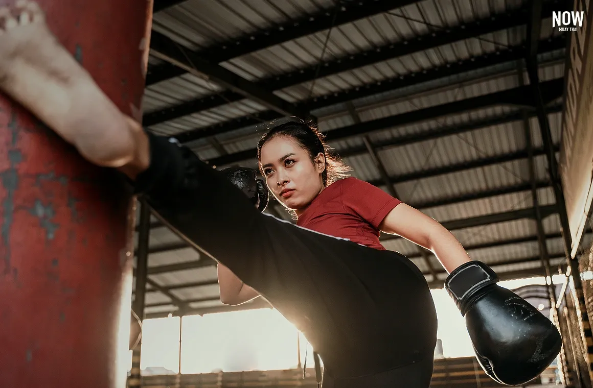 A woman executing rapid-response combo punches and defense drills with a partner during a Muay Thai pad work session.