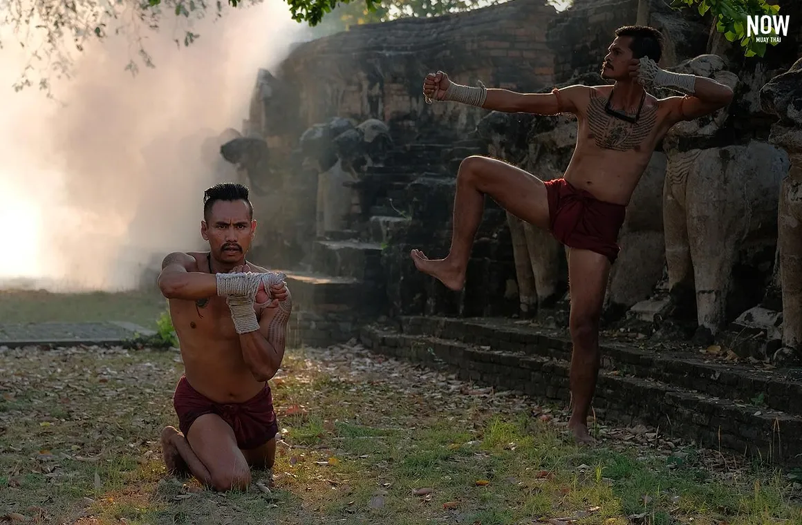 Two fighters performing the Wai Kru ritual in traditional Muay Boran attire, honoring their trainers and the spirit of Muay Thai before the match.