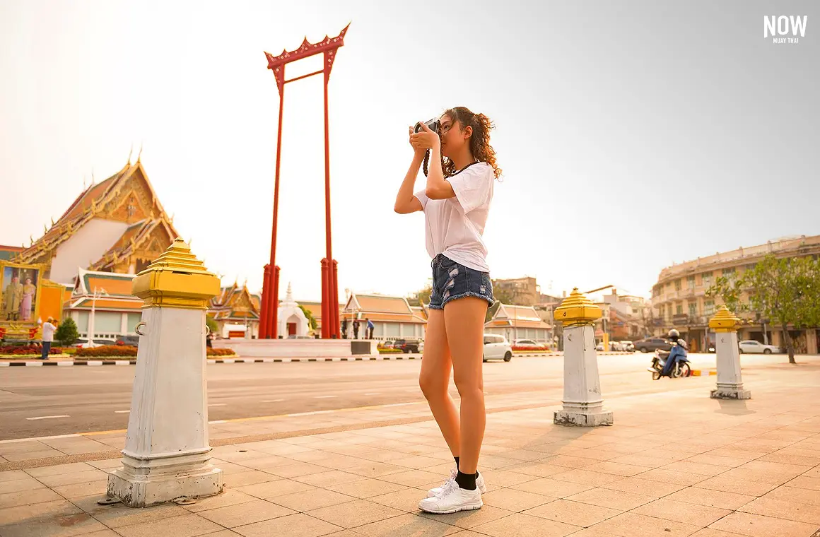  Beautiful young Asian tourist woman sightseeing in Bangkok, exploring the iconic Giant Swing and the stunning ordination hall of Wat Suthat, embracing the rich cultural heritage of Thailand.