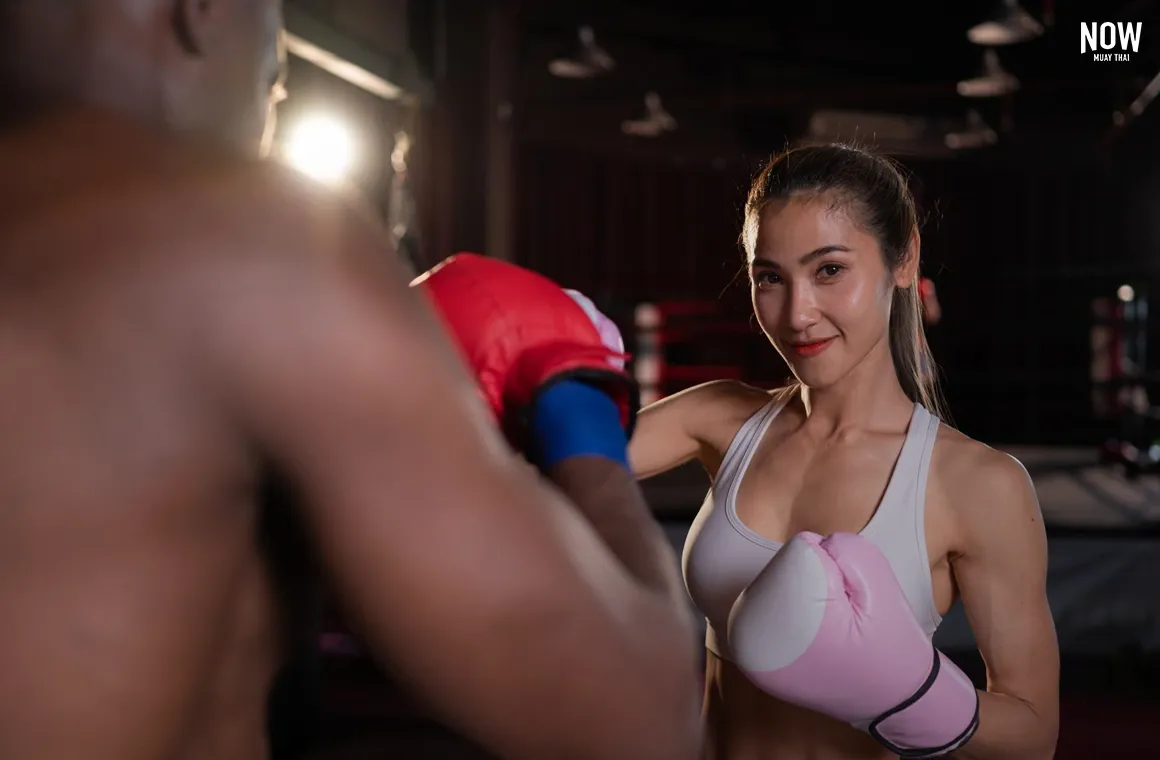 A woman training in Muay Thai, throwing a punch during an intense workout session, symbolizing strength and empowerment as part of the Fitness and Wellness Revolution