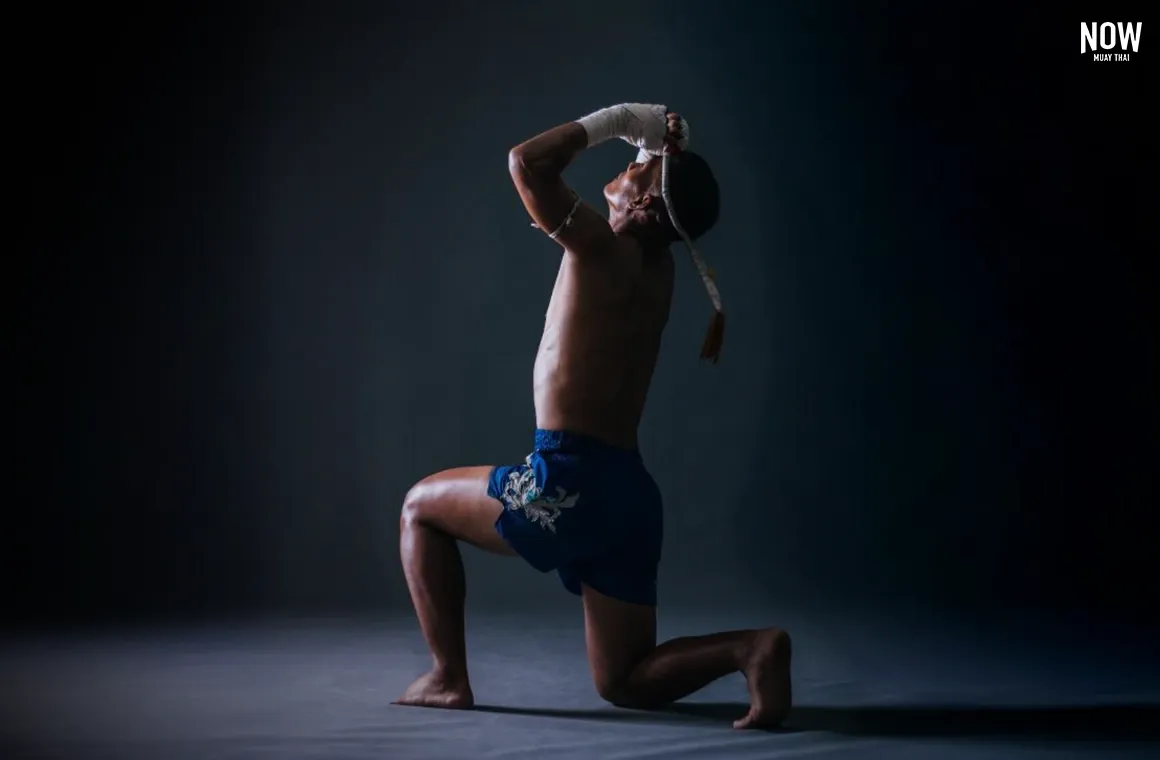 Muay Thai fighter performing the traditional Wai Kru ritual before a match, honoring their trainer and preparing for battle in the ring.