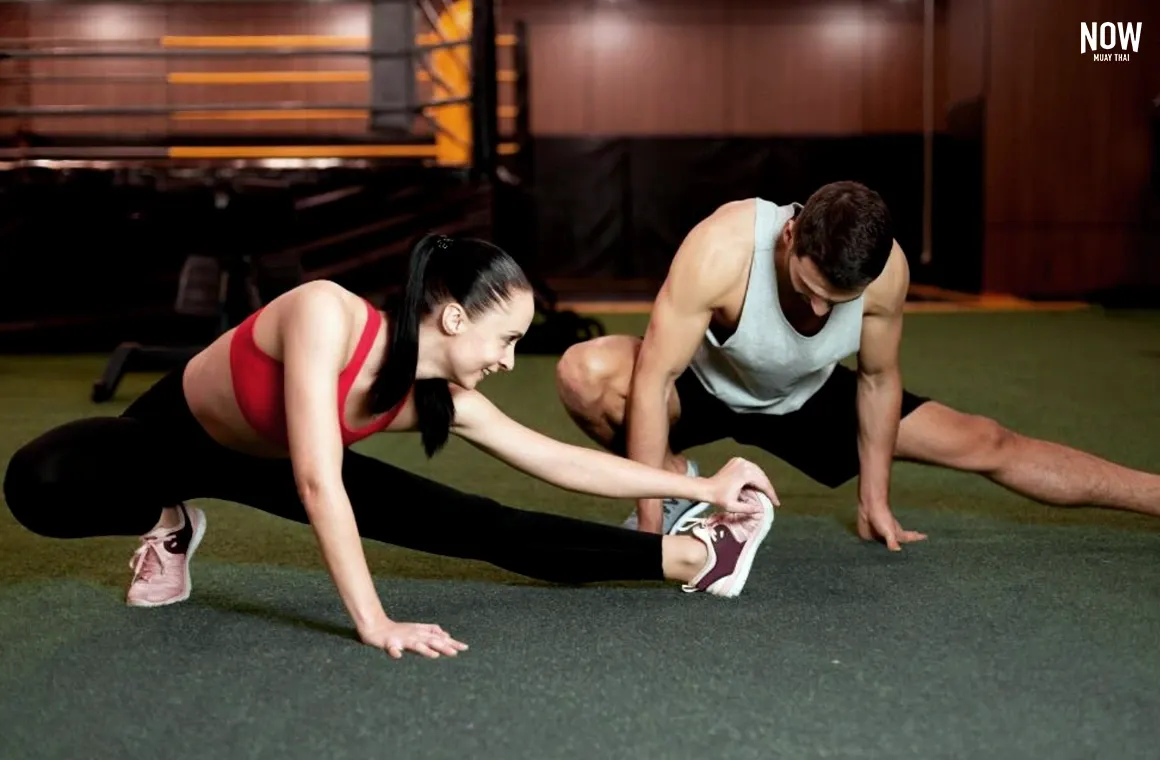 A Muay Thai student cooling down after an intense workout. The cool-down session, focusing on stretching, is crucial for relaxing muscles, improving flexibility, and preventing injury. It also helps reduce stress and promotes faster recovery after training. 