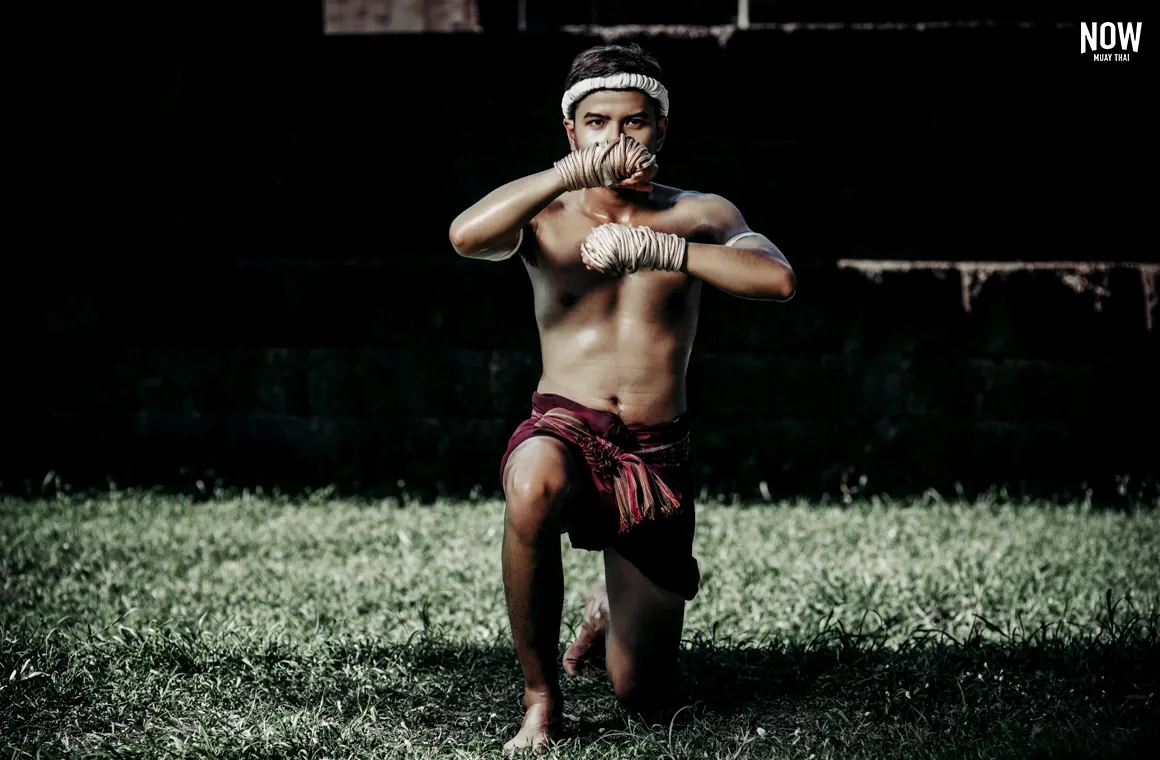 Muay Thai fighter performs the Wai Kru Muay Thai ritual, paying deep respect to his Kru in the sacred Kuen Kru ceremony. This act symbolizes his humility, dedication, and readiness to learn, marking his formal initiation into the world of Muay Thai under his teacher's guidance and wisdom.