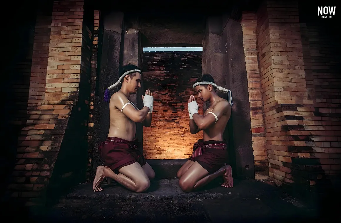 Two Muay Thai fighters performing the Wai Kru ritual, showing respect to their teachers and embracing the spirit of Thai culture before their match. The image captures the deep tradition and fighter’s discipline as they mentally prepare for the battle ahead.