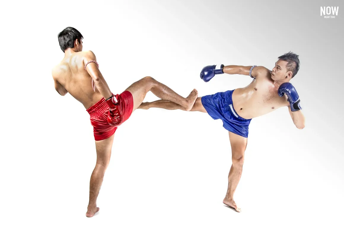 Two Muay Thai fighters demonstrate "Kon Muay Kae Tae," a defense against a kick. One fighter skillfully blocks a kick with his foot while preparing for a counterattack, highlighting the precise and strategic defense techniques in Muay Thai to neutralize powerful kicks.