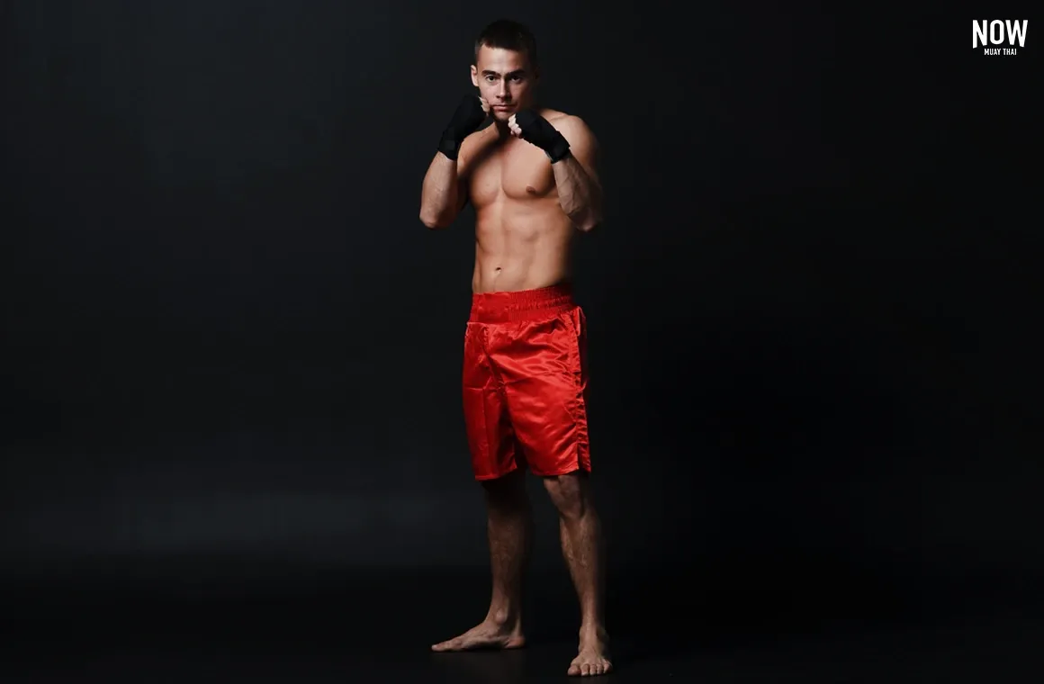 A Muay Thai beginner demonstrates a proper guard stance, focusing on fundamental positioning. This essential stance helps beginners build a solid foundation, ensuring correct form and balance as they progress to more advanced techniques in Muay Thai.