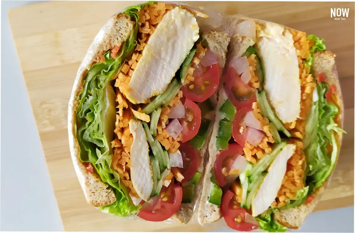 A visually appealing whole wheat sandwich filled with tender chicken breast and colorful fresh vegetables