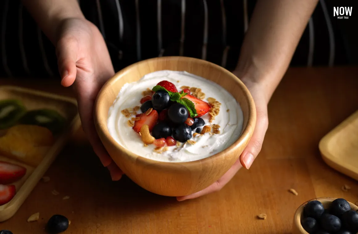 A bowl of Greek yogurt topped with almonds, mixed nuts, and fresh berries