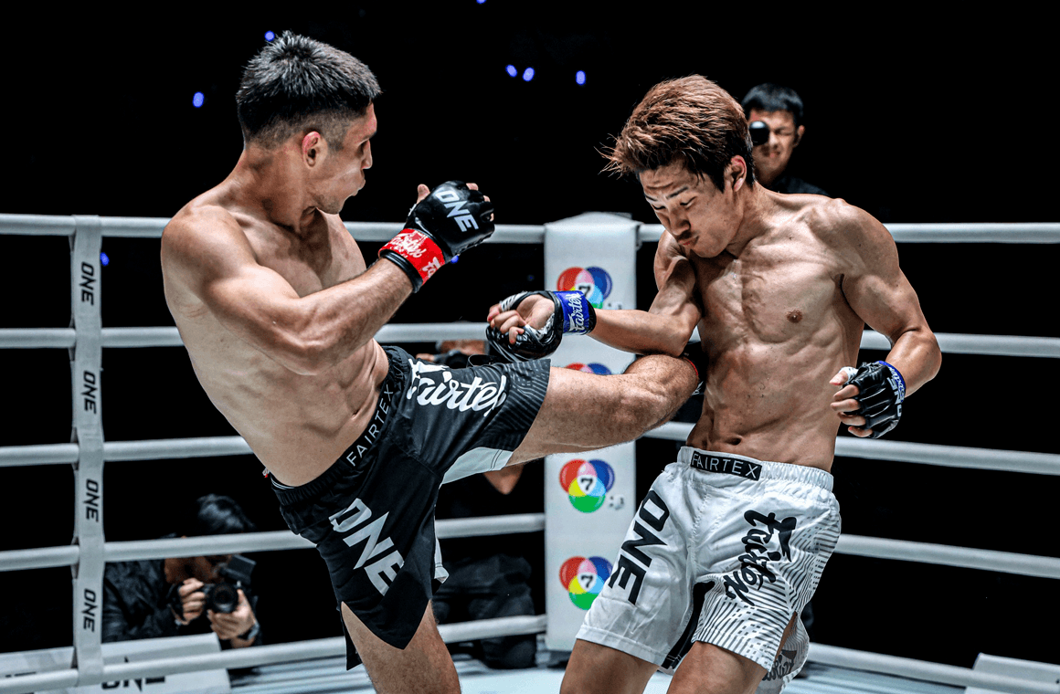 a fighter posing in front of ONE Lumpinee Wall at Lumpini Boxing Stadium