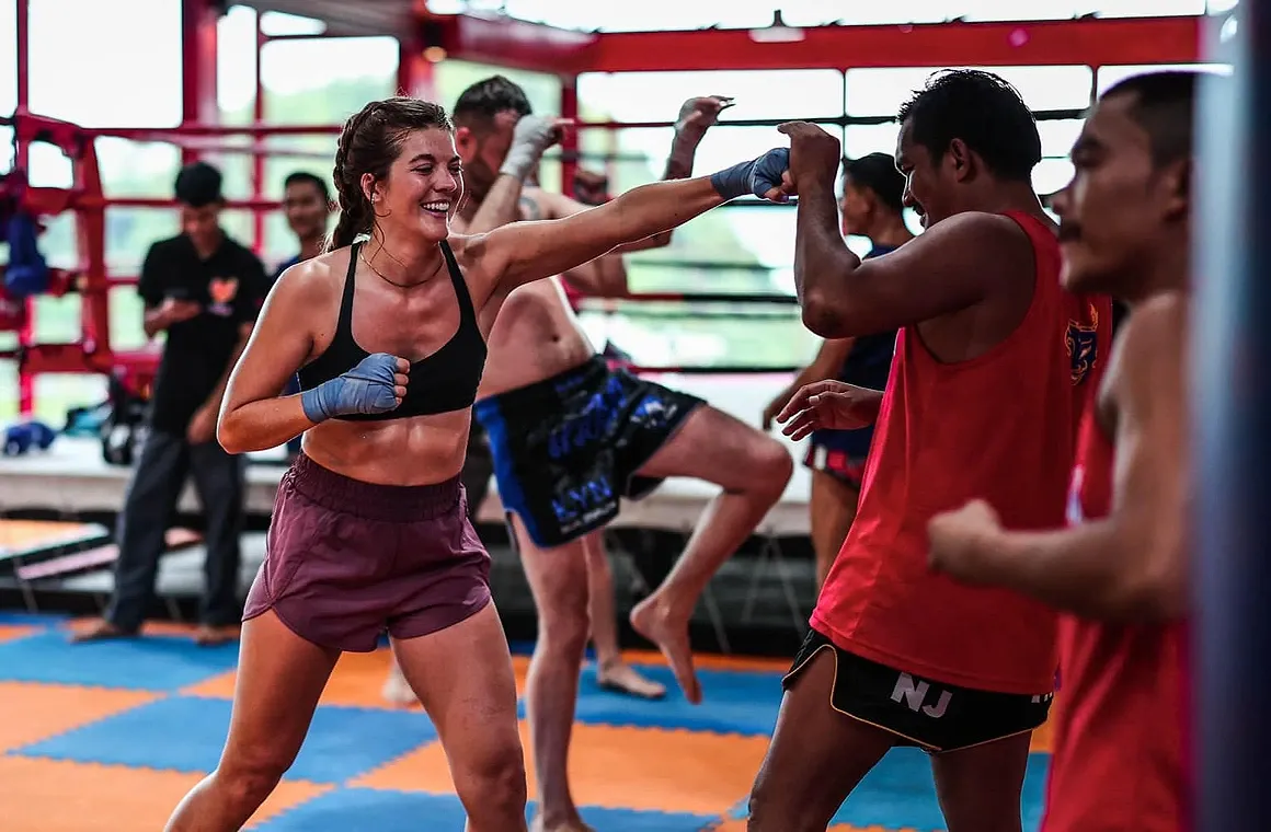 A young woman trains in a beginner-friendly Muay Thai class, featuring patient trainers, a supportive atmosphere, and tailored lessons - perfect for mastering fundamentals and building confidence in Thailand’s vibrant cultural setting.