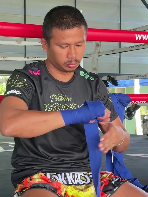 Superlek is wrapping his hands before starting his daily training session.