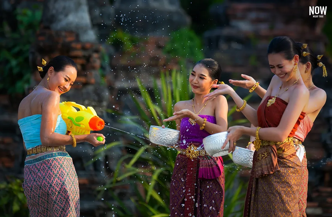 Thai girls in traditional dress splashing water during the Songkran Festival in Ayutthaya, Thailand, held every April. This lively celebration of Thai New Year, filled with water fights and cultural traditions, is a must-experience event for tourists.