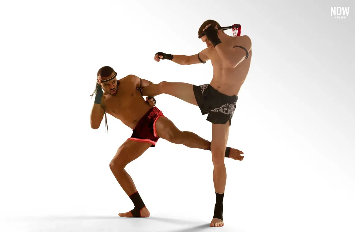 Two fighters demonstrate the advanced Muay Thai technique of catching a kick, followed by a counter attack with a sweep to the opponent's standing leg.