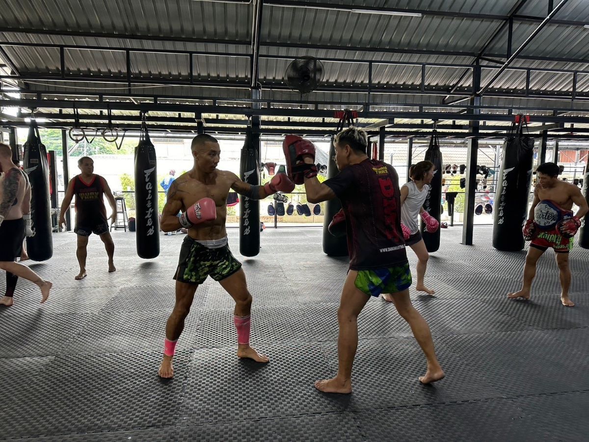 The trainer is practicing pad work with students during a group session.