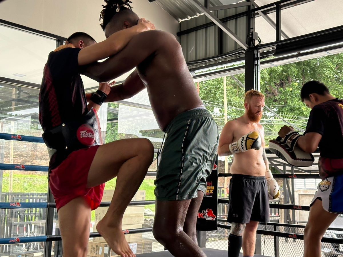 Trainer demonstrates the clinch technique during a group Muay Thai session.