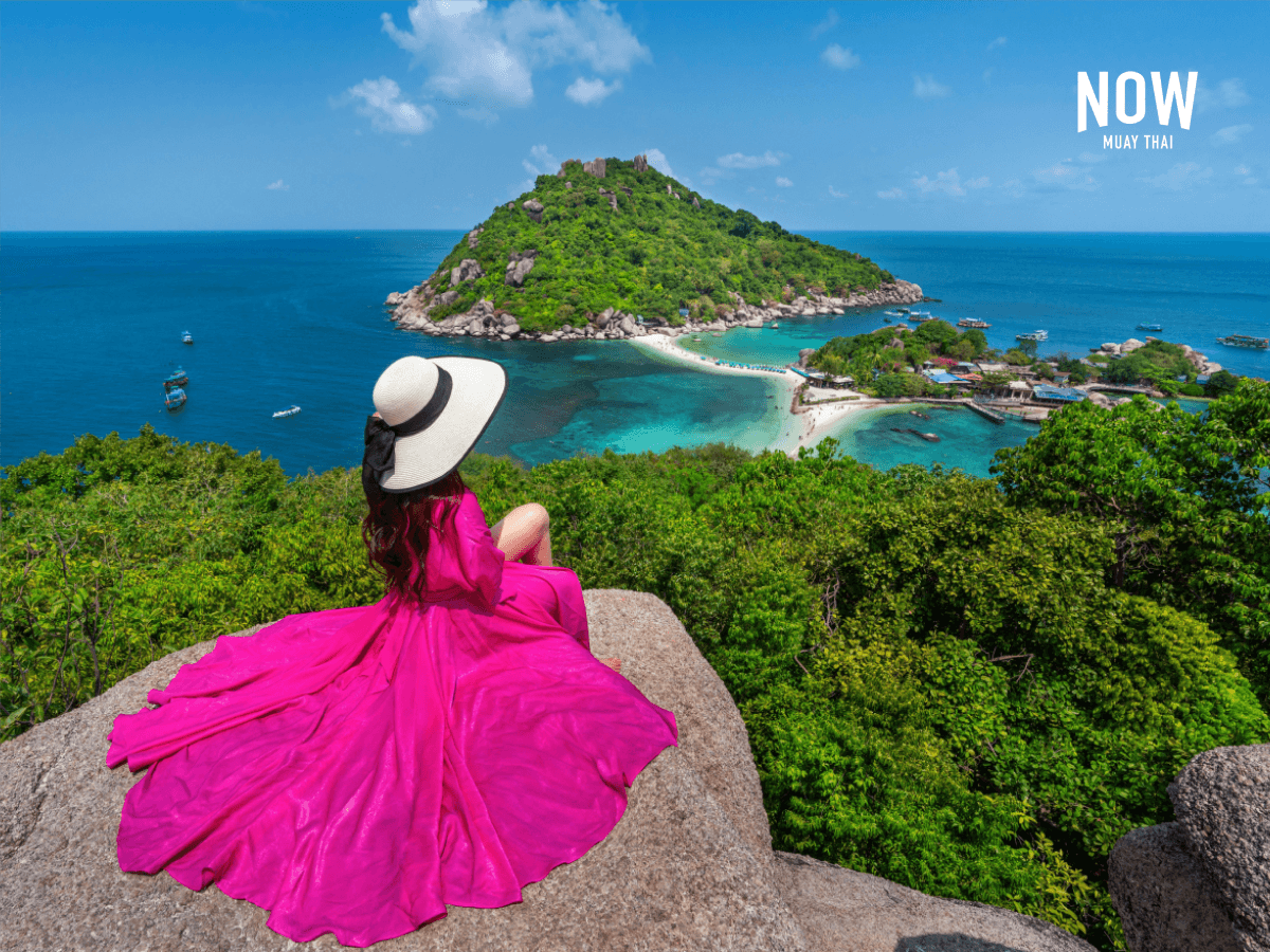 Woman in pink dress and sun hat sitting on a viewpoint on the island of Koh Nang Yuan near the island of Koh Tao