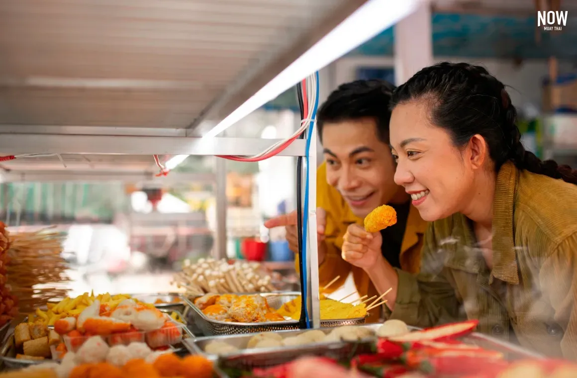 Two people browsing dishes at a local street food stall