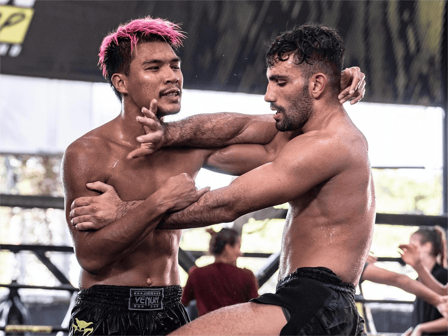 Two fighters from the Venum Training Camp Pattaya rehearse a Muay Thai clinch.