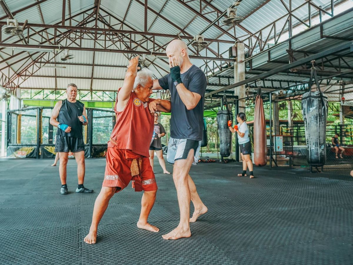 A Master Muay Thai trainer is teaching Muay Thai techniques to foreign students.